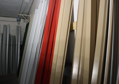 Vertical metal sheets in various colors stored in a warehouse.
