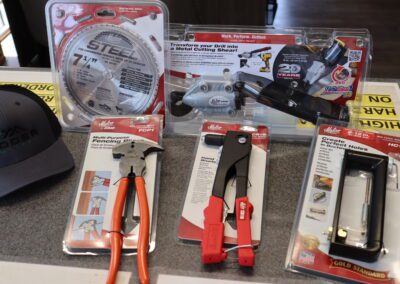 Assorted tools and a cap on a counter: metal cutting shears, a hand riveter, pliers, and a measuring template.