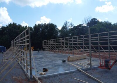 Wooden building frame construction site with workers and clear sky.