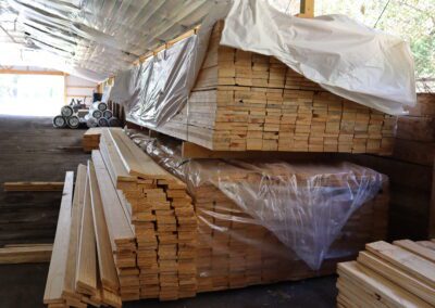 Stacks of treated lumber in a warehouse with labels indicating sizes.