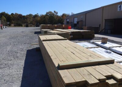 Stacks of treated lumber in a warehouse with labels indicating sizes.