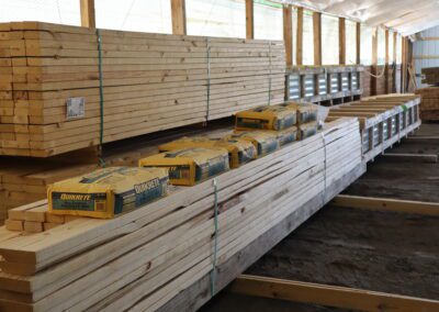 Stacks of treated lumber in a warehouse with labels indicating sizes.
