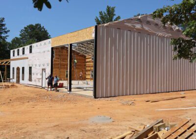 New construction house with exposed wooden framework and wrapped insulation, featuring windows and a door.