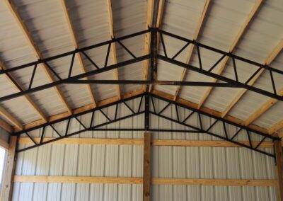 Interior of an empty metal barn with wooden framing and dirt floor.